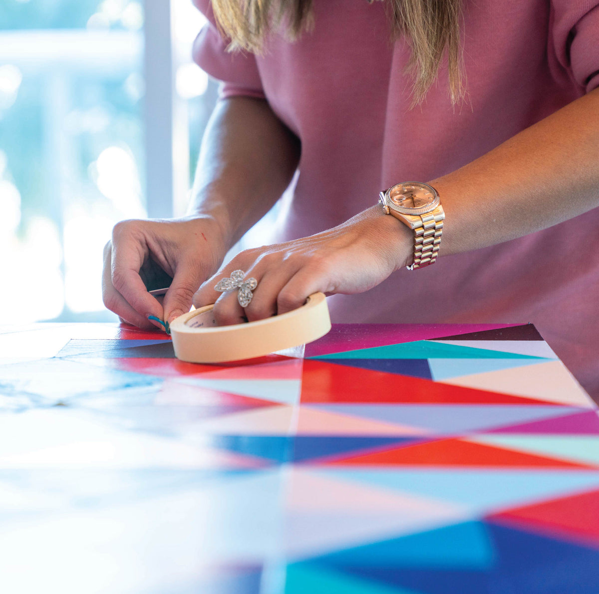 Hands resting on a hand-painted geometric table