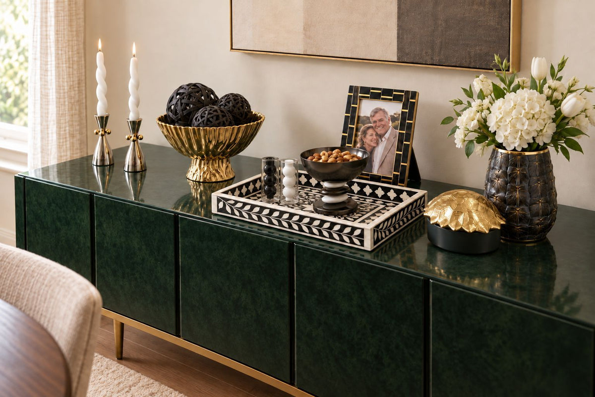 Green credenza styled scene with checkerboard tray, candlesticks, frame and vase