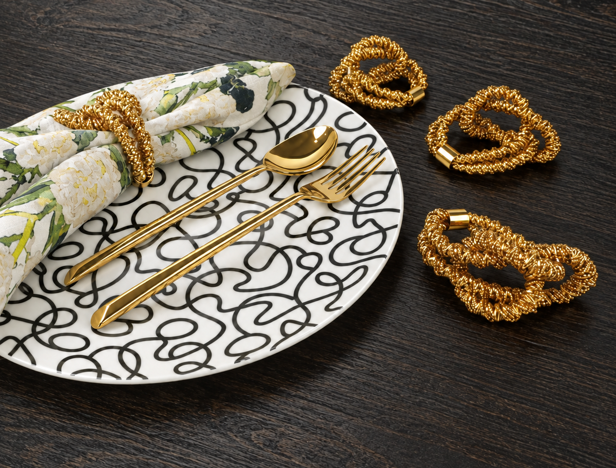 Black and white Squiggly plate with gold napkin rings and Cream Floral Garden napkin on black wood