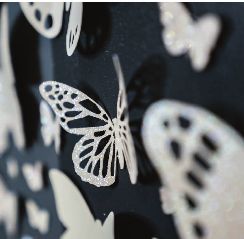 Hand-cut white butterflies on a black wall