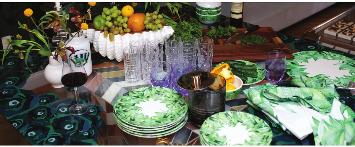 Long table set with green palm print melamine dinnerware and glassware